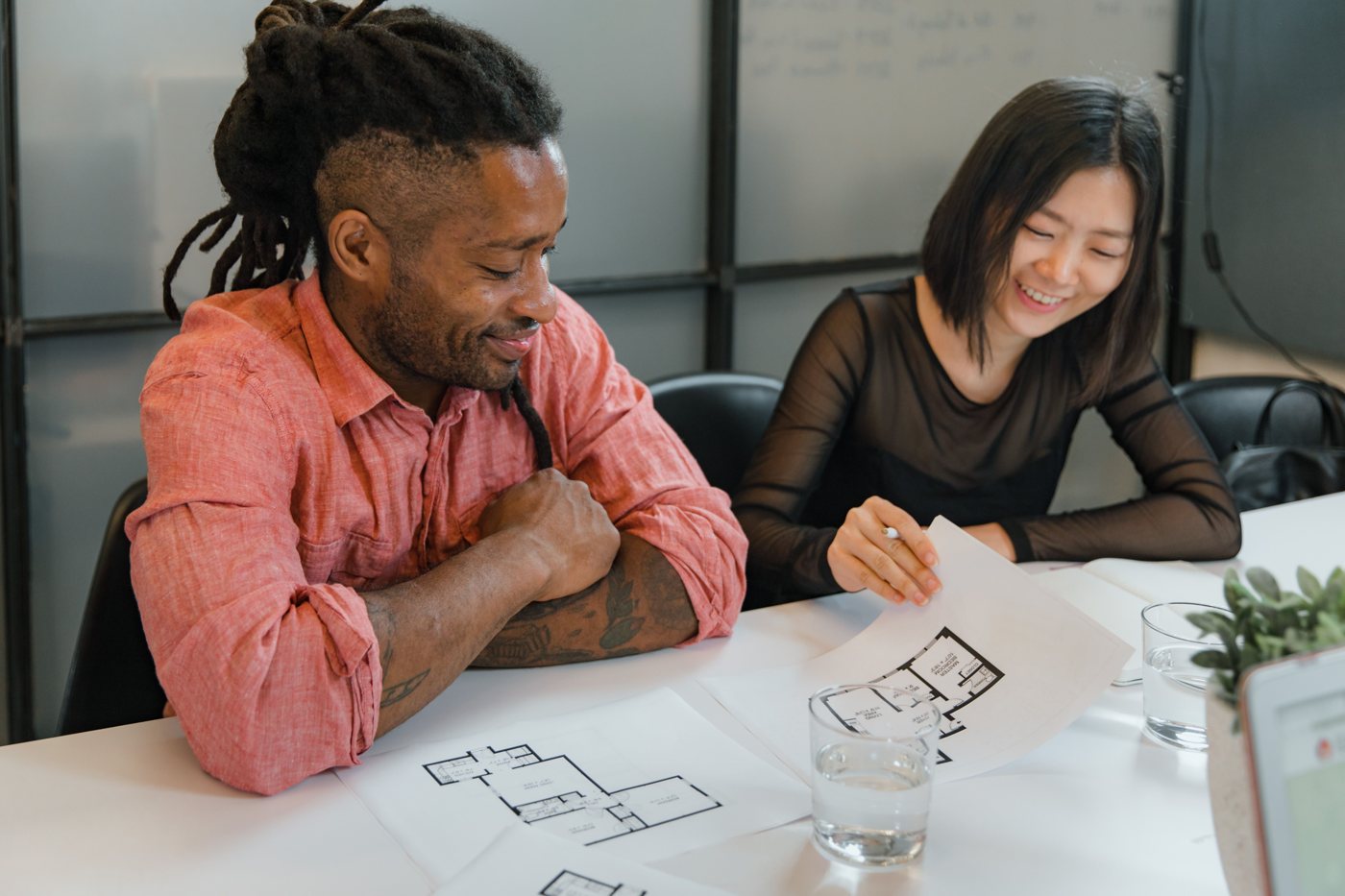 Two colleagues reviewing residential floor plans at a table